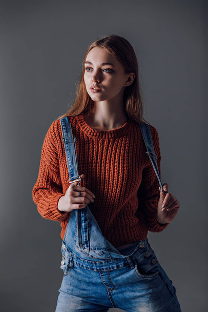 Young attractive woman in a red sweater on a gray background. - Fotoğraf, Görsel