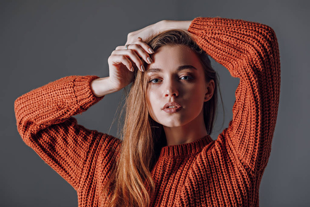 Mujer atractiva joven en un suéter rojo sobre un fondo gris
. - Foto, imagen