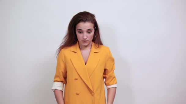 Shocked young woman in yellow jacketkeeping hand on head, looking confused - Πλάνα, βίντεο