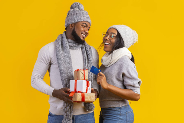 Affectionate Christmas couple holding gifts and credit card - Foto, imagen