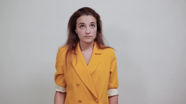 Aantrekkelijke jonge vrouw in gele jas spreidt handen, op zoek gelukkig - Video