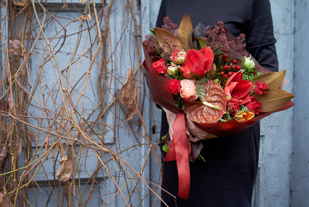 Fille tient chic bouquet d'automne dans des couleurs rouges dans un style vintage à l'extérieur sur le fond de raisins secs et une vieille porte, foyer sélectif
 - Photo, image