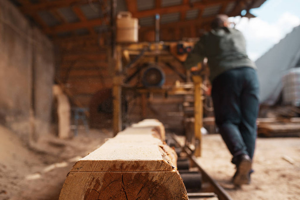 Menuisier travaille sur machine à bois, industrie du bois, menuiserie. Transformation du bois en usine, sciage forestier dans la cour à bois, sciage
 - Photo, image