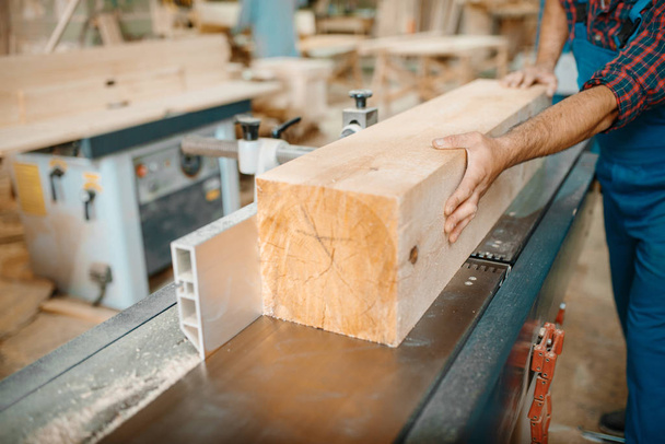 Carpinteiro processa feixe de madeira na máquina plana, madeira, indústria madeireira, carpintaria. Processamento de madeira na fábrica de móveis
 - Foto, Imagem
