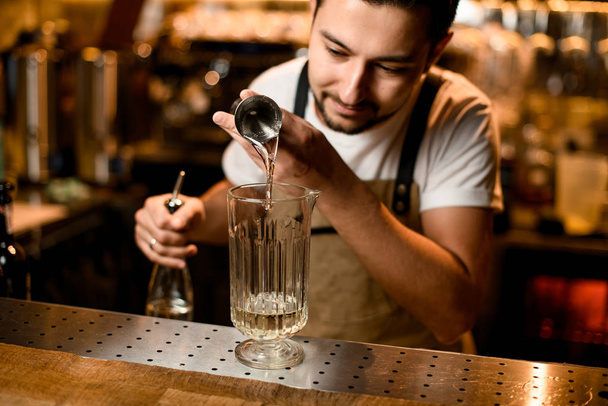 Bartender pouring a alcoholic drink from the jigger to a measuring glass cup - 写真・画像