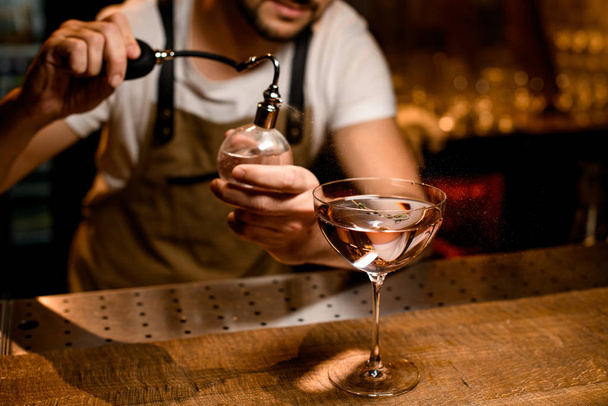 Professional male bartender spraying on the cocktail in the glass with a bitter - 写真・画像