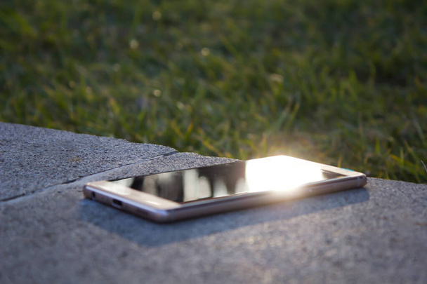 Makroaufnahme des Smartphones, vergessen auf Marmor im Park liegend - Foto, Bild