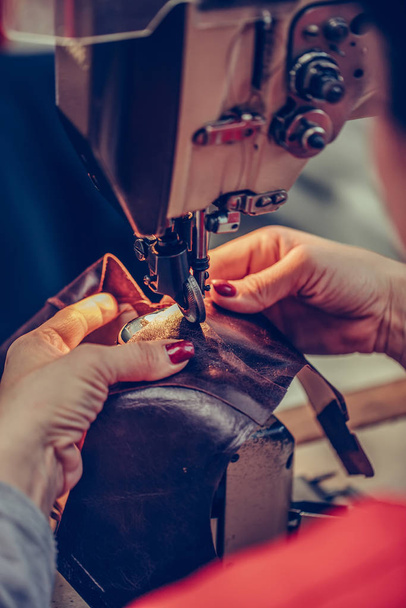 Frauenhände nähen einen Teil des Schuhs in einer Werkstatt - Foto, Bild