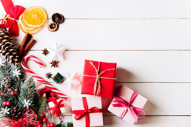 Красивая рождественская композиция на белом фоне с золотыми рождественскими подарочными коробками, снежными еловыми ветвями, хвойными конусами, праздничным декором. Вид сверху
 - Фото, изображение