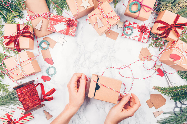 Рождественские подарки и ленты на белом мраморном фоне, женщина упаковывает рождественские подарки
 - Фото, изображение