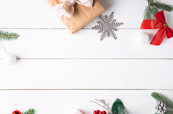 Красивая рождественская композиция на деревянном белом фоне с рождественскими подарочными коробками, снежными еловыми ветвями, хвойными конусами, сушеными фруктами с корицей, праздничным декором, карамельной палочкой. Новый год. Вид сверху, пространство для копирования
. - Фото, изображение