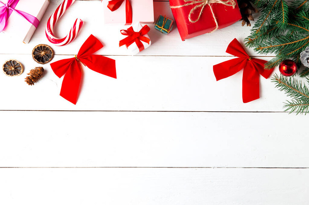 木製の白い背景に美しいクリスマスの組成。クリスマスプレゼントボックス、雪のモミの枝、針葉樹コーン、キャラメルスティック、贈り物。新年。トップビュー、コピースペース. - 写真・画像