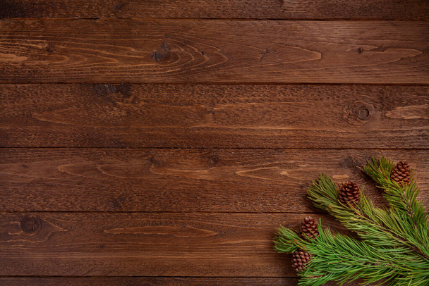 最小限のクリスマス構成。暗い、木製の背景にコーンで枝を発芽させます。クリスマス、冬のコンセプト。フラットレイアウト、トップビュー. - 写真・画像