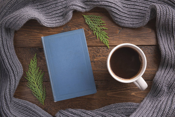 Winter, cozy composition. Warm scarf, book and cup of coffee, on wooden background. Flat lay, top view, copy space. - Φωτογραφία, εικόνα