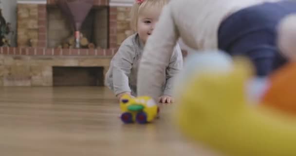 Cute Caucasian baby girl and her little sister crawling on the floor at home. Happy sisters having fun indoors. Leisure, resting, childhood, lifestyle. Cinema 4k ProRes HQ. - Filmagem, Vídeo