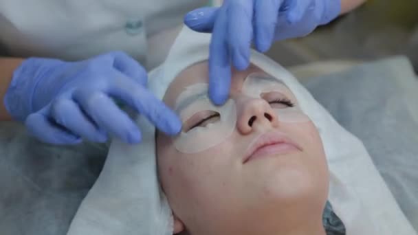 Szakmai kozmetikus nő alkalmazó arc maszk ügyfél. - Felvétel, videó