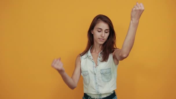 Vrolijke blanke jonge vrouw in blauw denim shirt houdt vuisten omhoog, glimlachend - Video