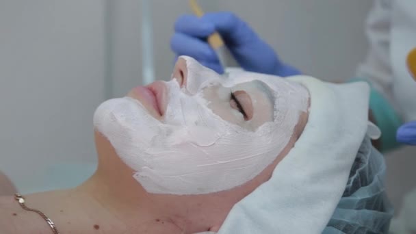 Szakmai kozmetikus nő alkalmazása maszk ügyfél arc ecset. - Felvétel, videó