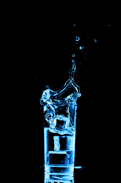vaso de agua con hielo sobre fondo negro - Foto, imagen