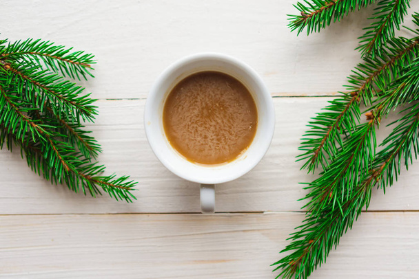 Χριστουγεννιάτικη σύνθεση - φλιτζάνι καφέ και έλατο κλαδιά σε λευκό ξύλινο φόντο. Επίπεδη θέα. Καλά Χριστούγεννα και Ευτυχισμένο το Νέο Έτος - Φωτογραφία, εικόνα