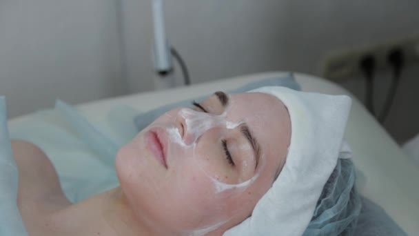 Όμορφη γυναίκα ξαπλώνει με μια μάσκα στο πρόσωπό της σε ένα σαλόνι ομορφιάς.. - Πλάνα, βίντεο