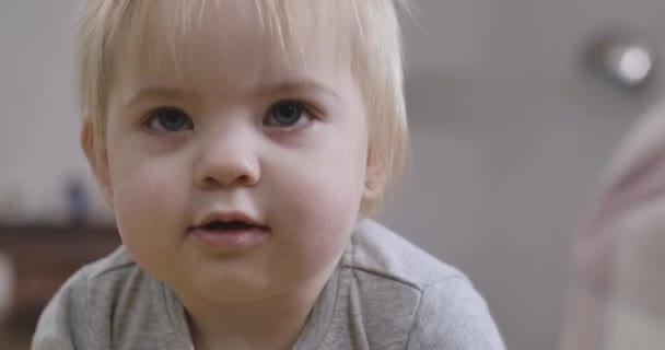 Close-up face of beautiful Caucasian baby girl with grey eyes and blond hair looking up with open mouth. Portrait of charming child. Cinema 4k ProRes HQ. - Metraje, vídeo