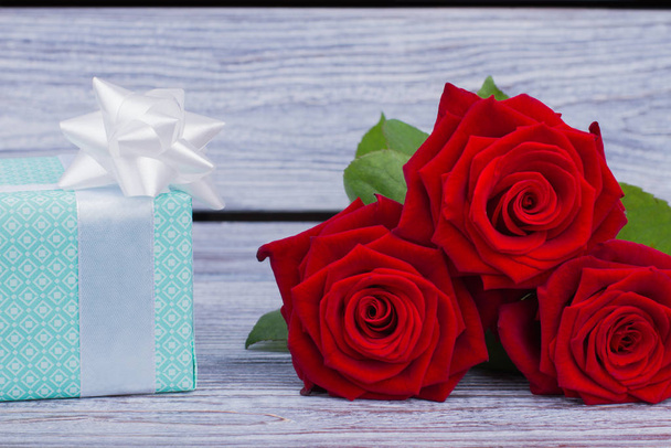 Cerca de rosas rojas y caja de regalo azul
. - Foto, Imagen