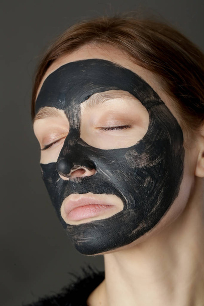 Charcoal face mask or black clay mud. Beautiful woman with black mask on her face, close up studio head shot. Natural cosmetic concept. - Zdjęcie, obraz