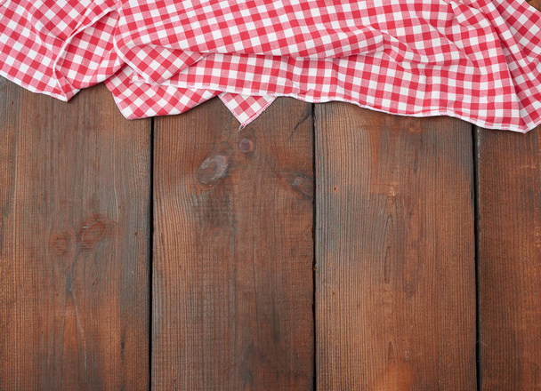 witte rode geruite keukendoek op een bruine houten achtergrond - Foto, afbeelding