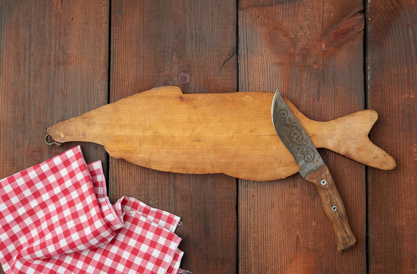 houten snijplank in de vorm van een vis en een scherp mes - Foto, afbeelding