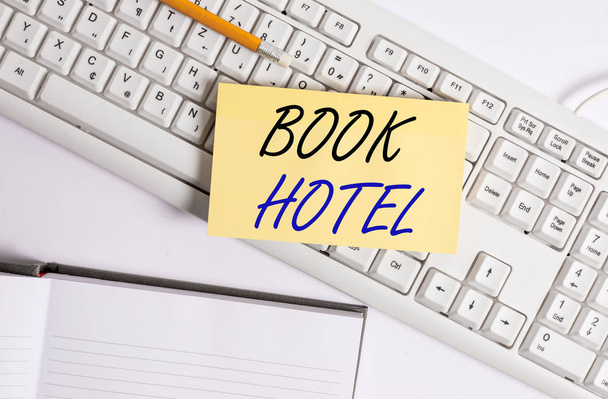 Szövegíró szöveg Book Hotel. Üzleti koncepció egy megállapodás, hogy egy szállodai szoba vagy szállás Fehér pc billentyűzet üres jegyzet papír és gemkapcsok felett fehér háttér. - Fotó, kép