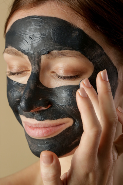Holzkohle-Gesichtsmaske oder schwarzer Lehm. Schöne Frau mit schwarzer Maske im Gesicht, Kopfschuss aus nächster Nähe. Naturkosmetisches Konzept. - Foto, Bild