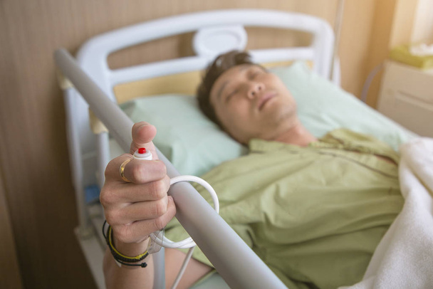 Um homem num quarto de hospital a chamar uma enfermeira. Mão segurando emergência b
 - Foto, Imagem