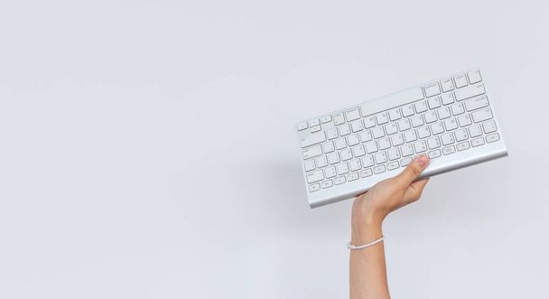 Business, hart arbeiten Konzept. Hand hält Tastatur-Computer mit weißem Hintergrund - Foto, Bild