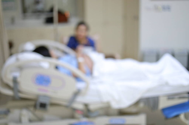immagine sfocata di paziente donna che riposa sul letto all'interno della sala di recupero in ospedale
 - Foto, immagini