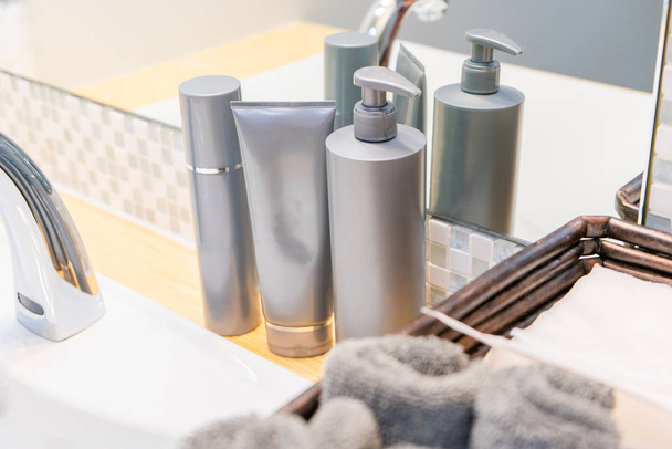 Skincare termékek, beleértve a toner, arc mosás, és szivattyú folyadék szürke palack fürdőszoba mosogató, mutató kéztörlő és papírtörlő, a rutin bőrápolás és higiénia. - Fotó, kép