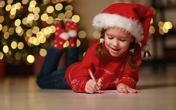 happy child girl writing letter santa home near Christmas tre - Zdjęcie, obraz