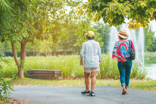 Обратный вид на счастье подруг, идущих вместе рядом с фонтаном в общественном парке. - Фото, изображение