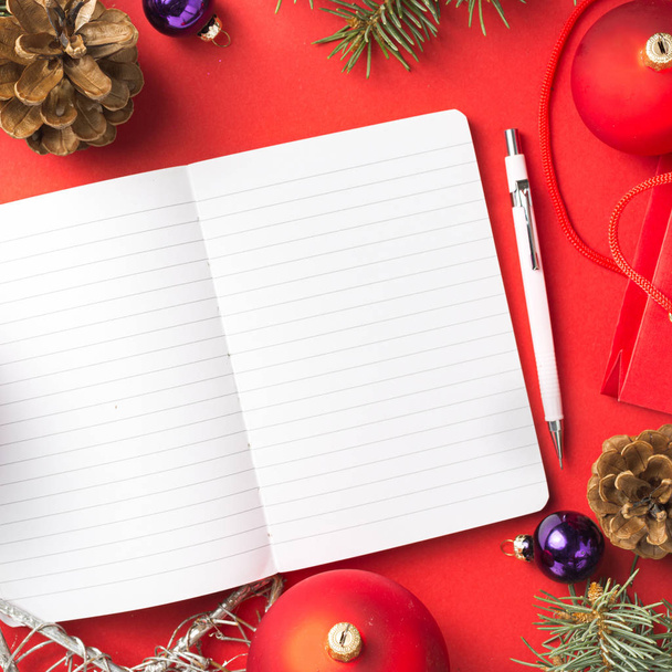 Notepad with Christmas decorations on a red desktop top view - 写真・画像