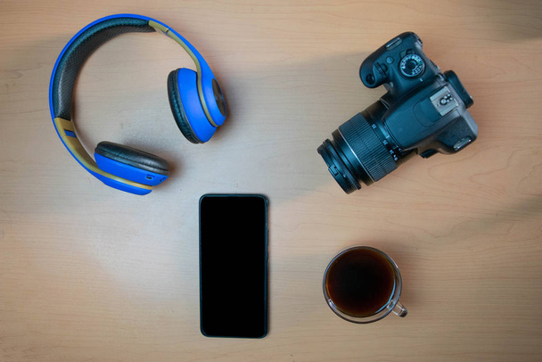 Composición de viajero con cámara, auriculares, café y smartphone en escritorio de madera
 - Foto, Imagen