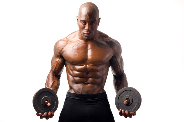 Black bodybuilder posing with round discs. Strong man with perfect abs, shoulders,biceps, triceps and chest. Isolated on white background - Foto, Bild