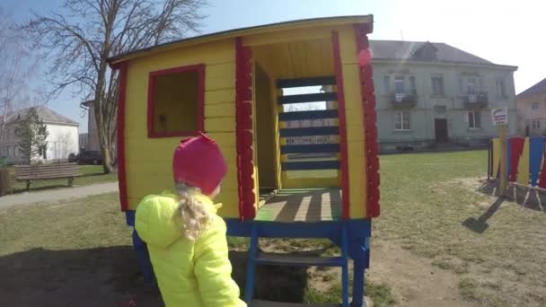 Cute girl wprowadzić kolorowy plac zabaw dla dzieci. Kobieta dziecko patrzeć przez okno - Materiał filmowy, wideo