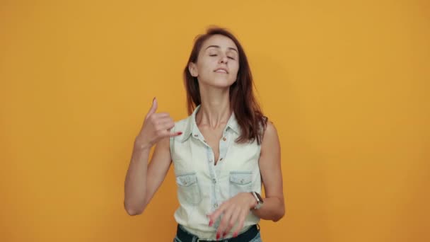 Pretty caucasian young woman in blue denim shirt doing phone gesture - Footage, Video