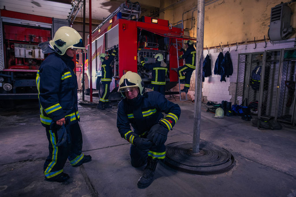 Bomberos que preparan su uniforme y el camión de bomberos de la ba - Foto, imagen