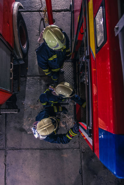 Bomberos que comprueban el motor de fuego dentro del departamento de incendios desde - Foto, Imagen