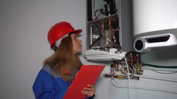 Técnico femenino hacer mantenimiento de la caldera de calefacción en casa privada
 - Imágenes, Vídeo