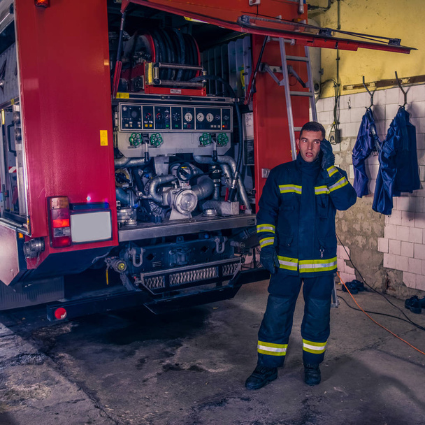 Un bombero reparando el motor de bomberos en la estación de bomberos. - Foto, imagen