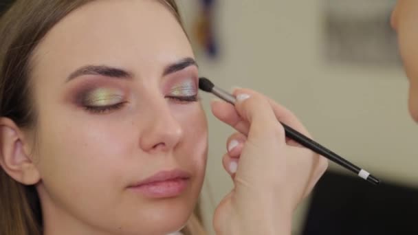 Professionele make-up kunstenaar zet oogschaduw op een klant van een schoonheidssalon. - Video