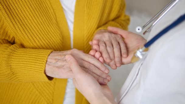 病院で看護師やシニア女性の手を握る医師のクローズアップ - 映像、動画