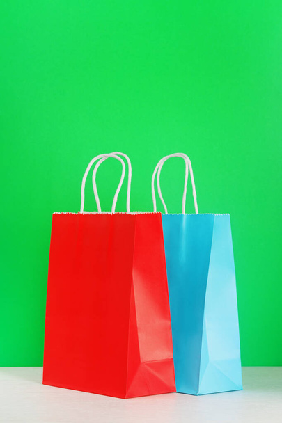 Red and blue shopping or gift bag on wooden desk against green background. - Foto, imagen